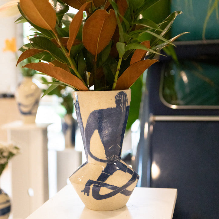 Flowers in a decorative vase by Damion Fuller on a table with a blurred background