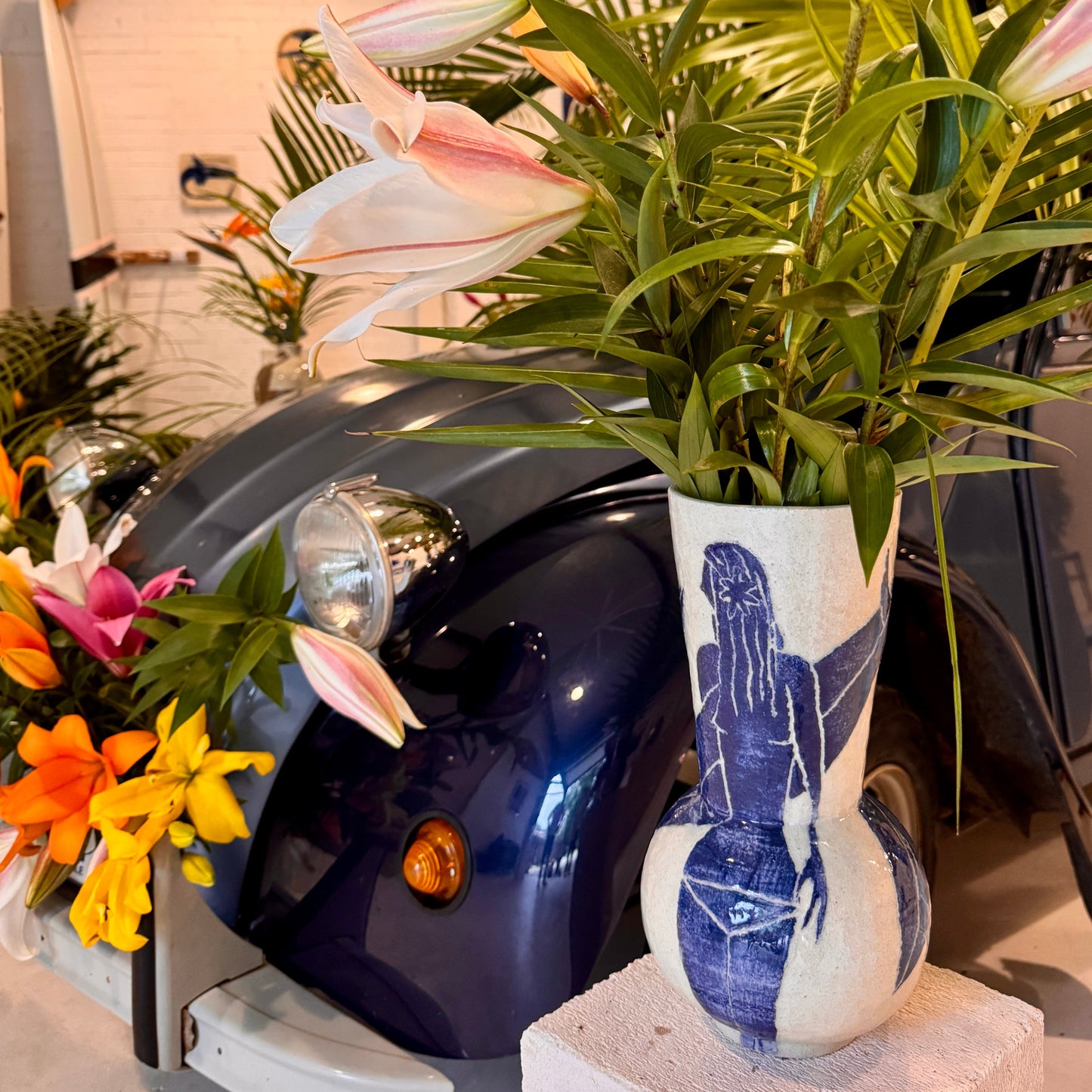 Decorative vase by Damion Fuller with artistic design on a motorcycle with flowers and plants.